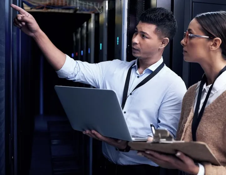 Two engineers reviewing a server rack together