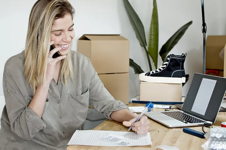 A business owner smiling on a mobile call at her desk